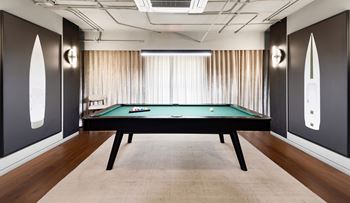 A pool table in a room with dark walls and a light-colored carpet.